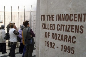 People stand in front of a monument with the names of 1,226 victims killed in the summer of 1992 at the beginning of the Bosnian war, during a ceremony to mark the 19th anniversary of the war, in the village of Kozarac